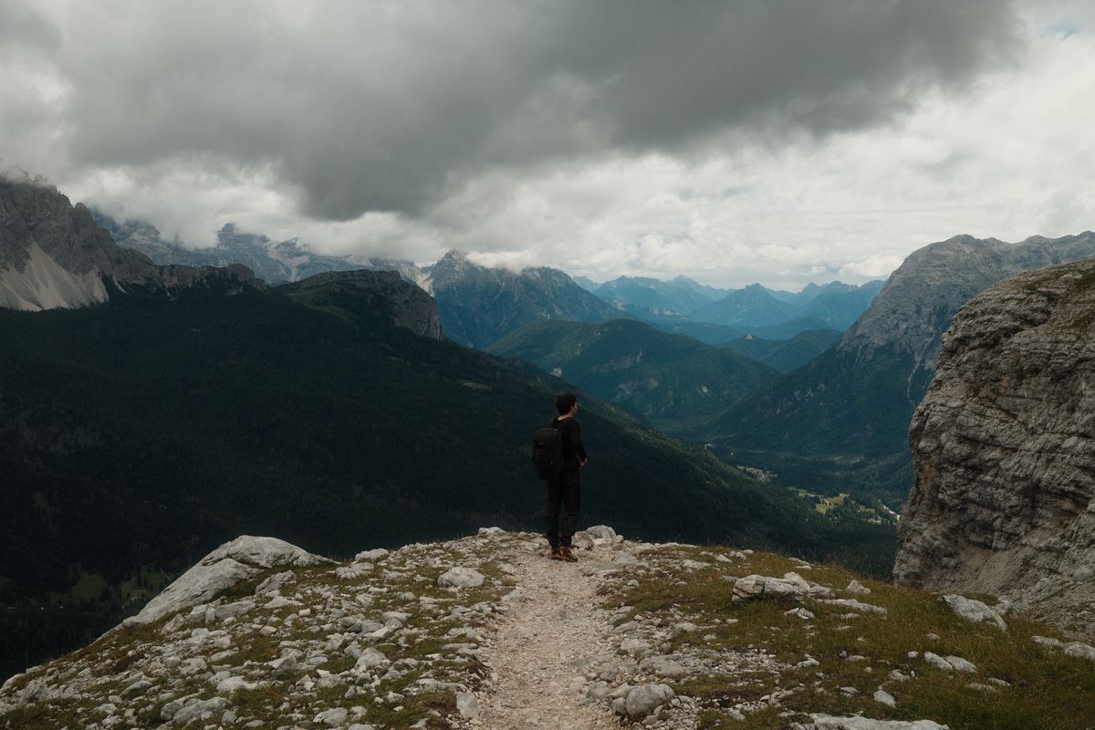 Figure on a ledge above a mountain valley